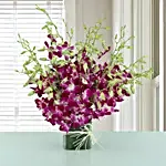 Exotic Expression 20 purple orchids in a glass vase with white Rassi knot