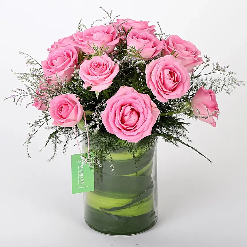 Glass vase arrangement of 15 pink roses, seasonal filler and draceane leaves
