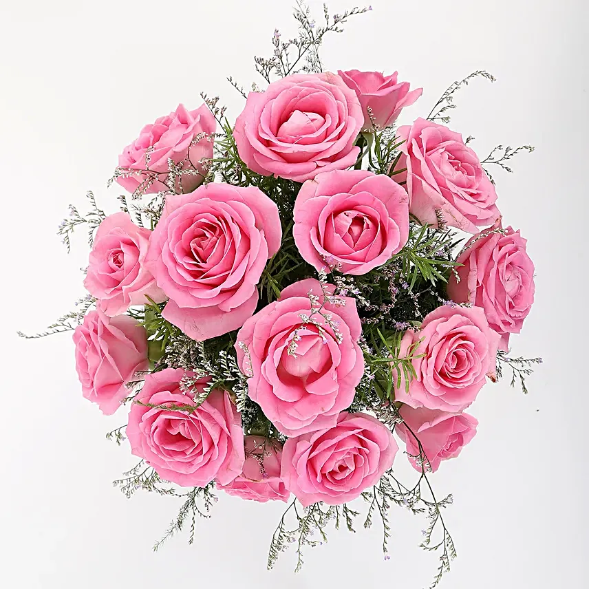 Glass vase arrangement of 15 pink roses, seasonal filler and draceane leaves