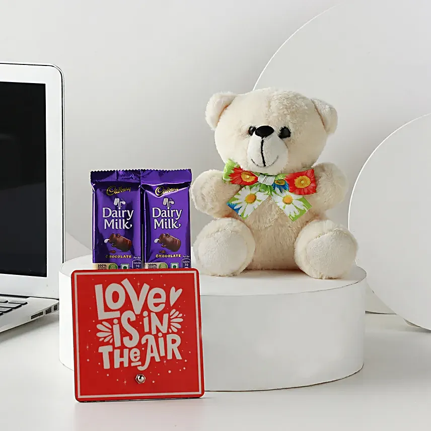 A hamper containing table top, dairy milk , cream teddy bear and a love message gifts