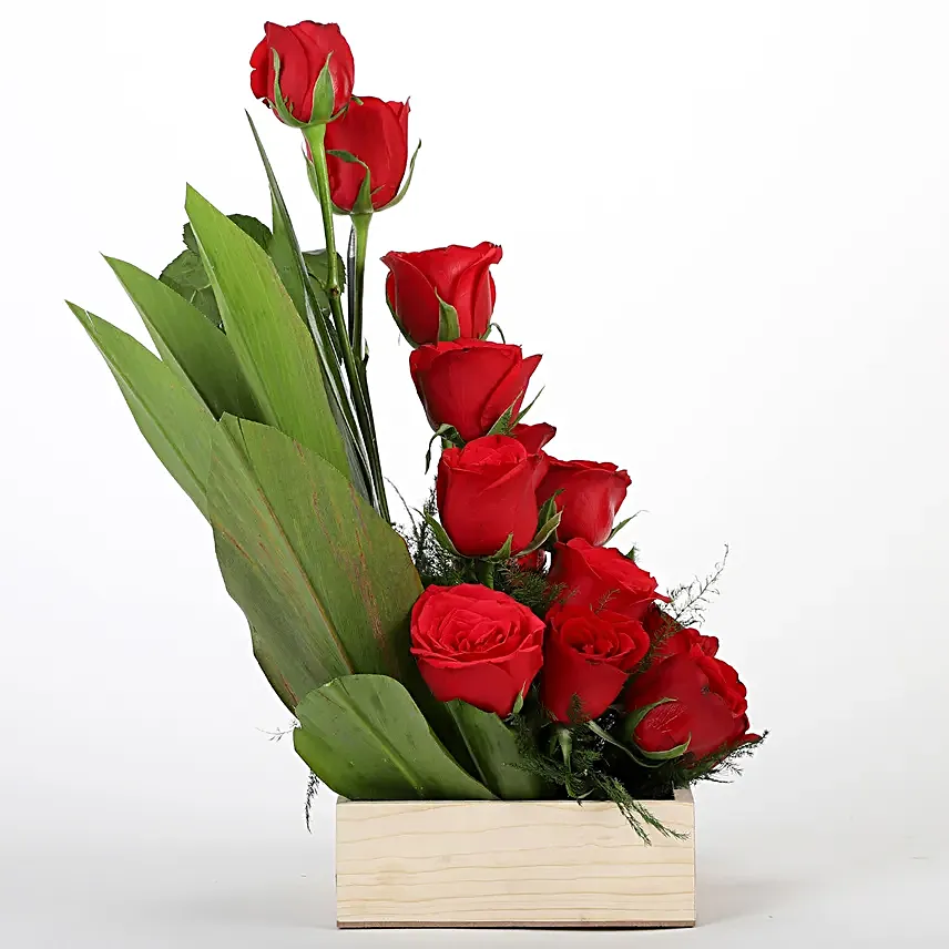 Cane basket arrangement of 15 red roses, draceane leaves and seasonal filler