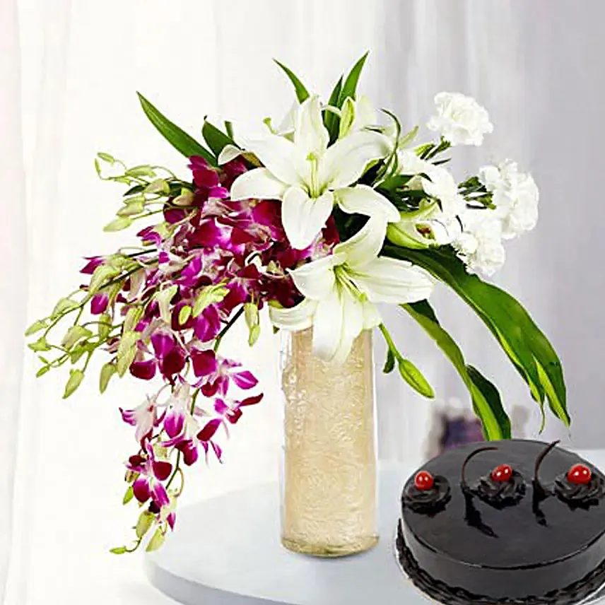 Combo of a glass vase arrangement of 6 purple orchids, 3 white asiatic lilies, 6 white carnations, draceane leaves and vase filler, with 500 grams truffle cake