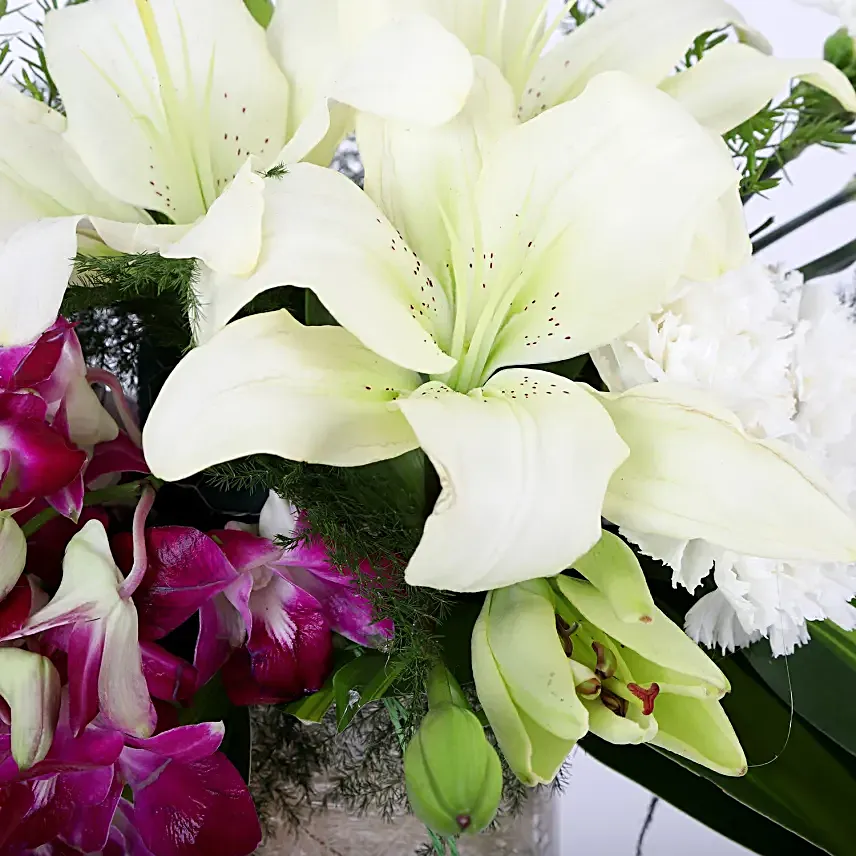Combo of a glass vase arrangement of 6 purple orchids, 3 white asiatic lilies, 6 white carnations, draceane leaves and vase filler, with 16 pieces of ferrero rocher chocolates